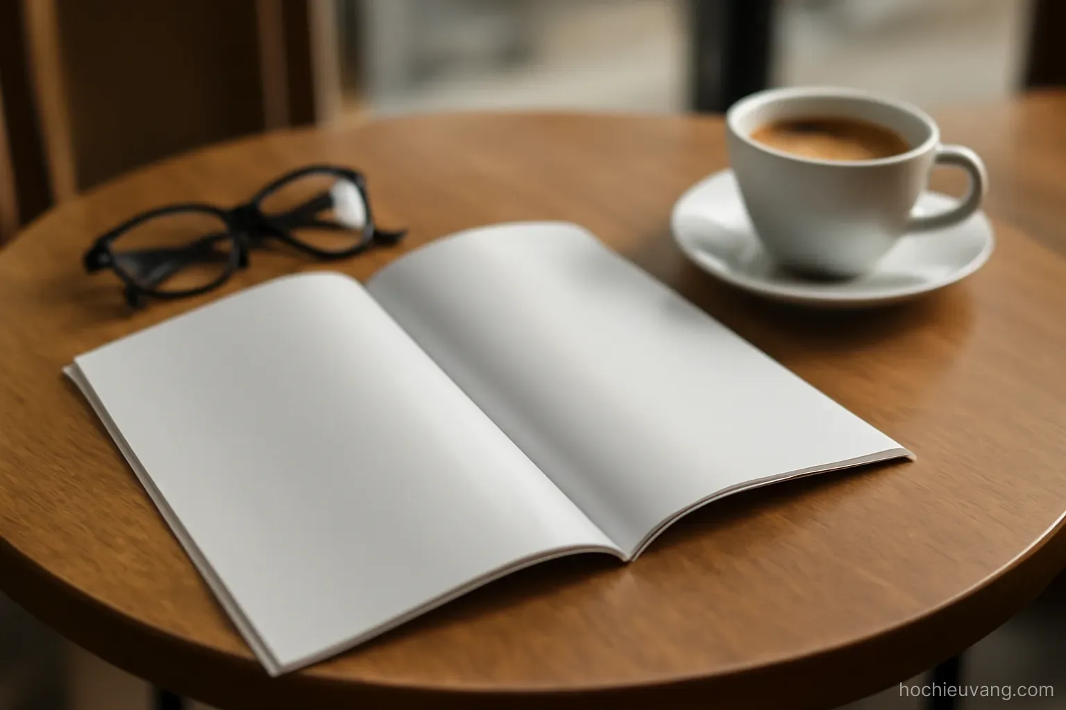 a glossy brochure lying open on a cafe table next to a cup and a pair of reading glasses